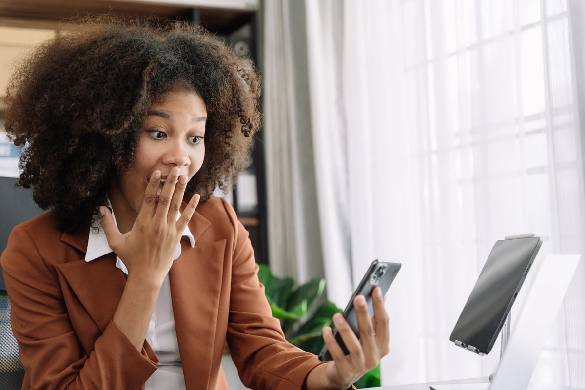 Excited african, american woman sitting at table feeling happy black woman overjoyed accepting mail at laptop promoted at home surprised girl reading good news.