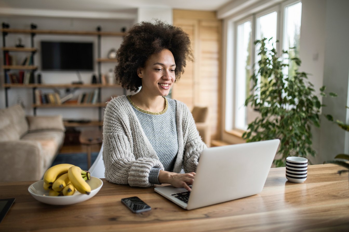 Beautiful black woman blogging on her computer at home.